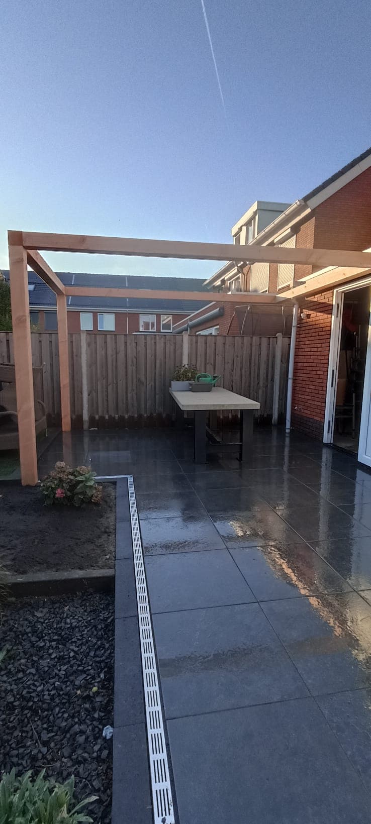 Dark porcelain terrace at blue hour under a timber pergola
