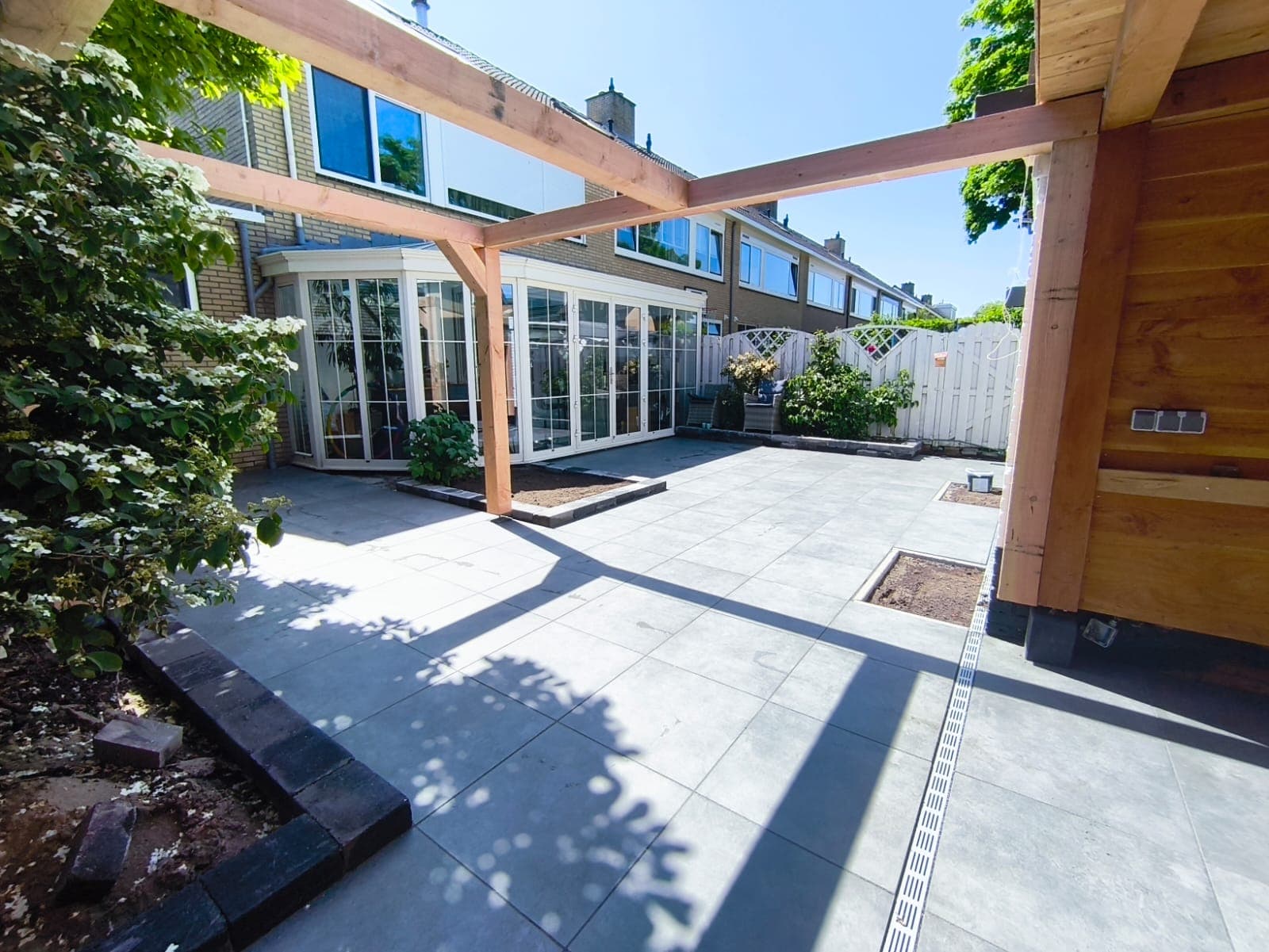 Sunny view through a timber pergola over a grey porcelain patio