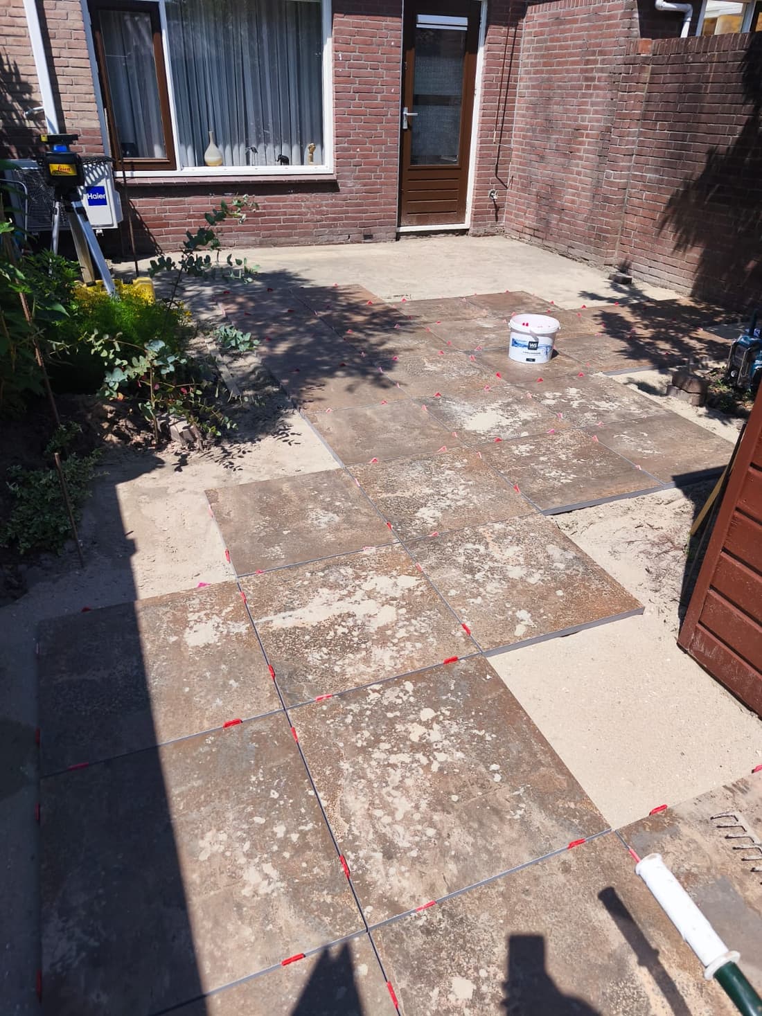 Porcelain tiles being laid with levelling clips and a laser level