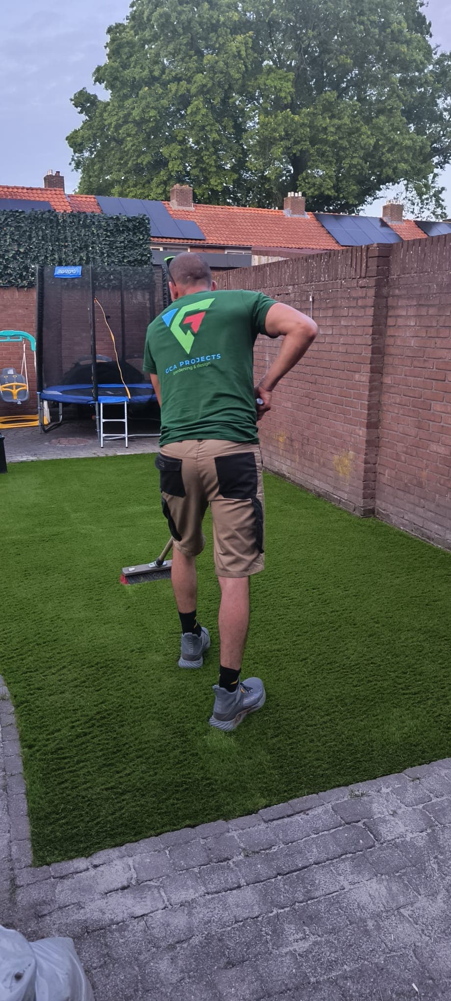 GCA crew member brushing a freshly installed artificial lawn