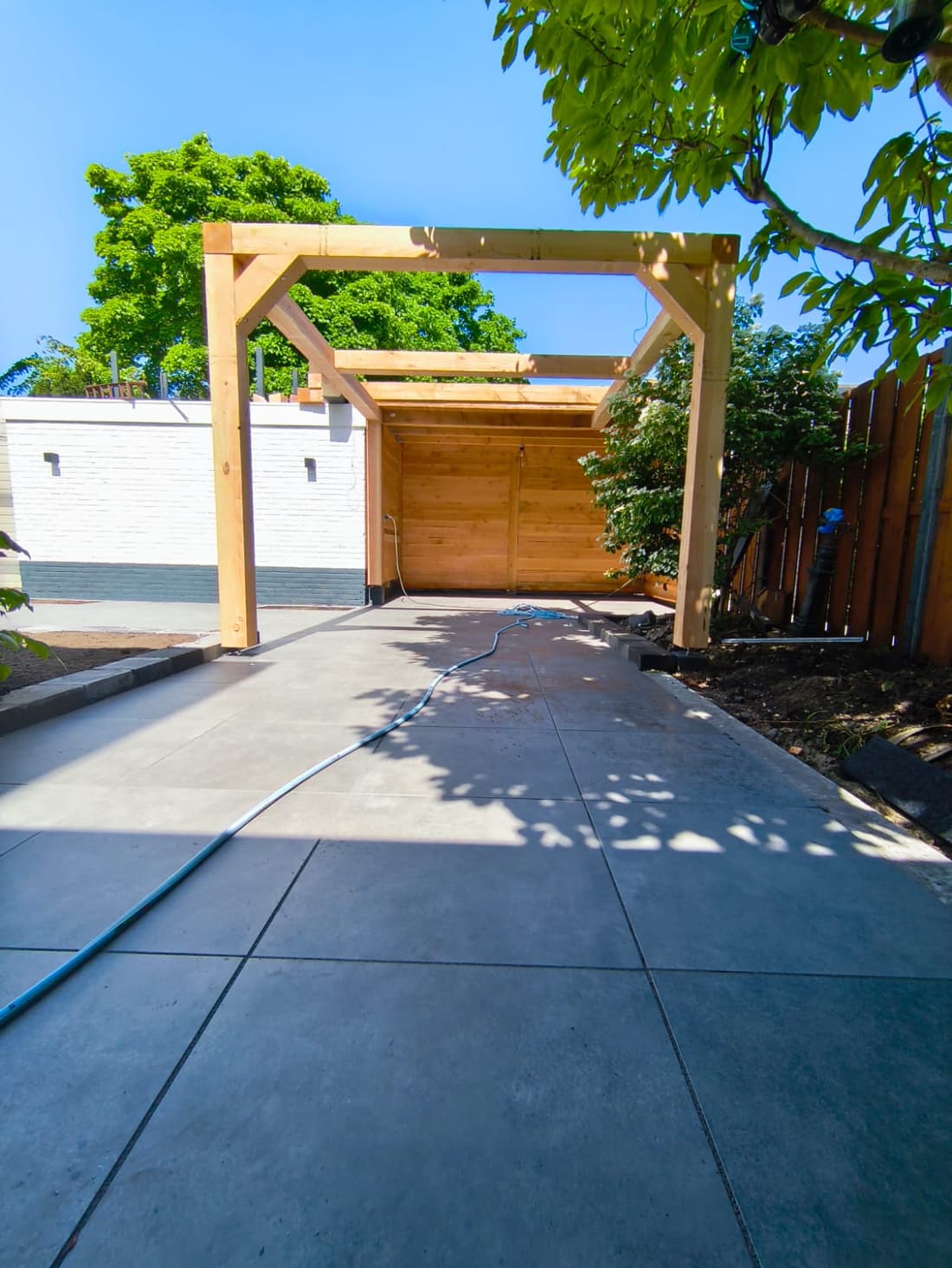 Douglas fir pergola frame over a dark porcelain path